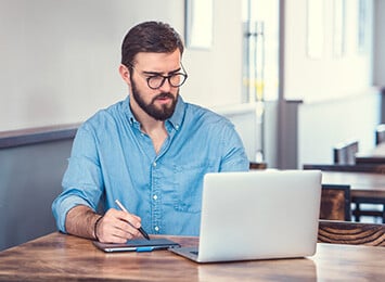 man som sitter ved et skrivebord og bruker en laptop